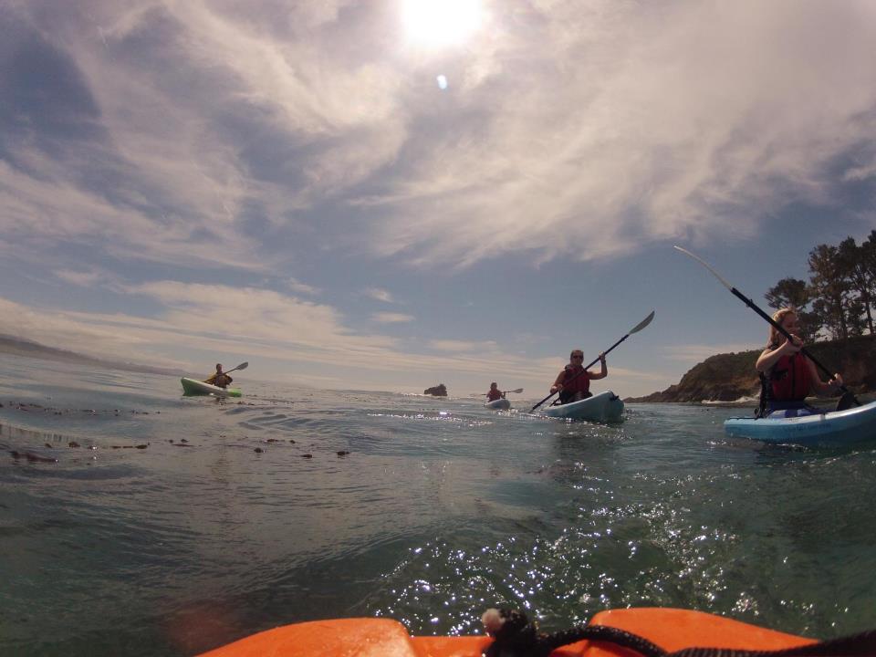 Group of kayakers from the perspective of the end of a boat
