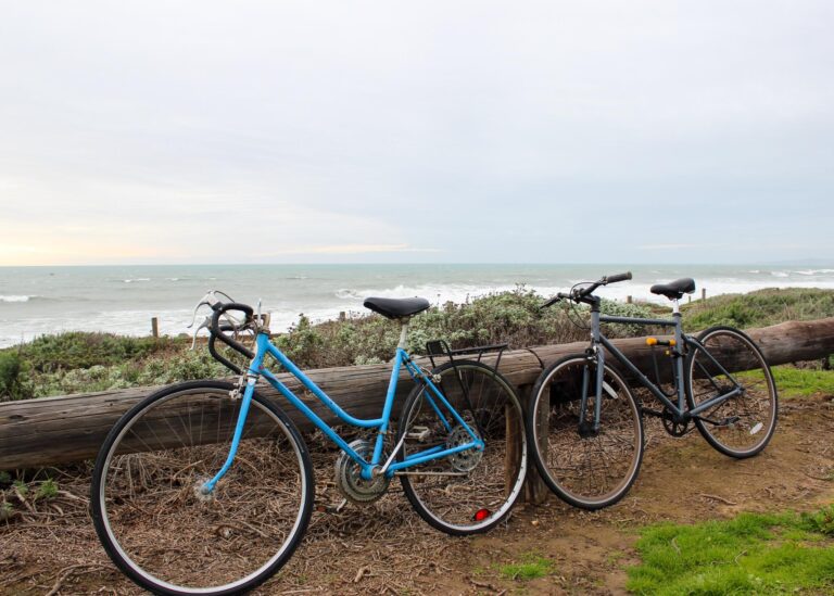 Two bicycles resting against a wooden ledge near the ocean in Cambria, California