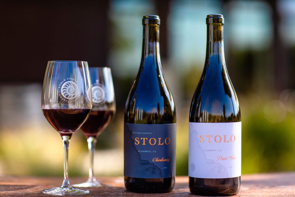 A glass of wine sits between two bottles, inviting you to unwind and enjoy a relaxing moment.